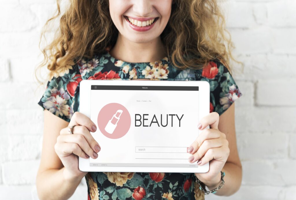 Mujer mostrando diseño digital con la palabra BEAUTY en tablet, representando el enfoque estético en marcas de belleza