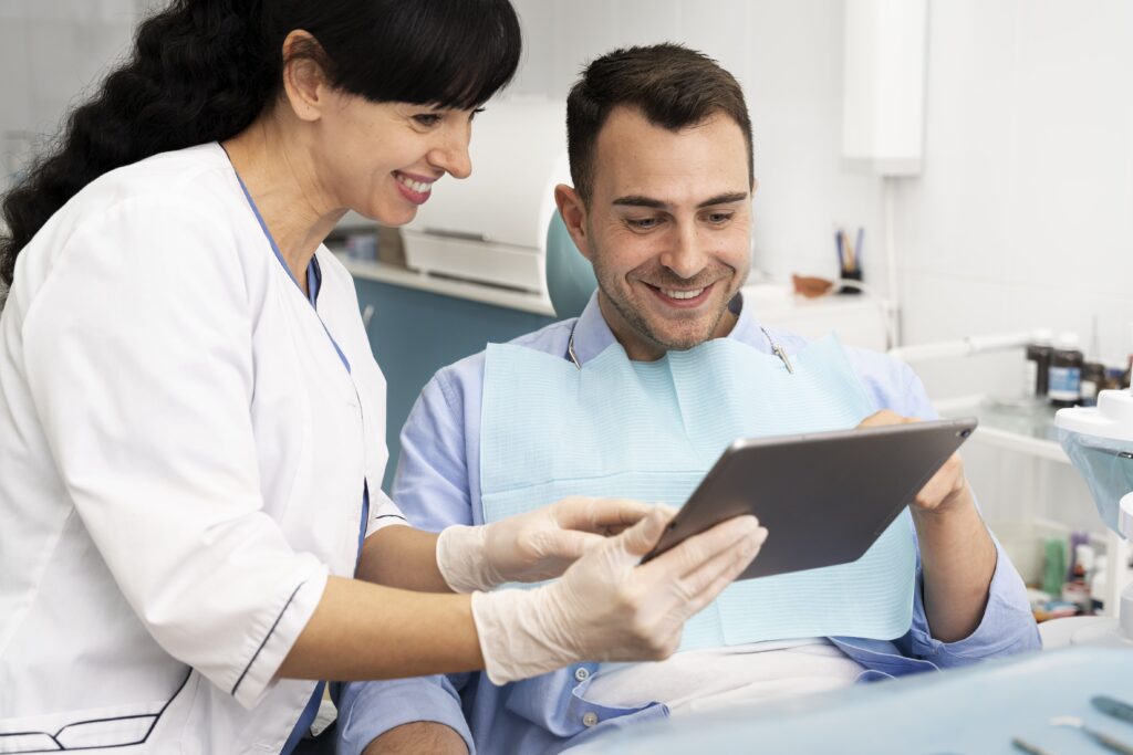 Dentistas revisando datos en pantalla con paciente, representando una atención personalizada y profesional en salud dental