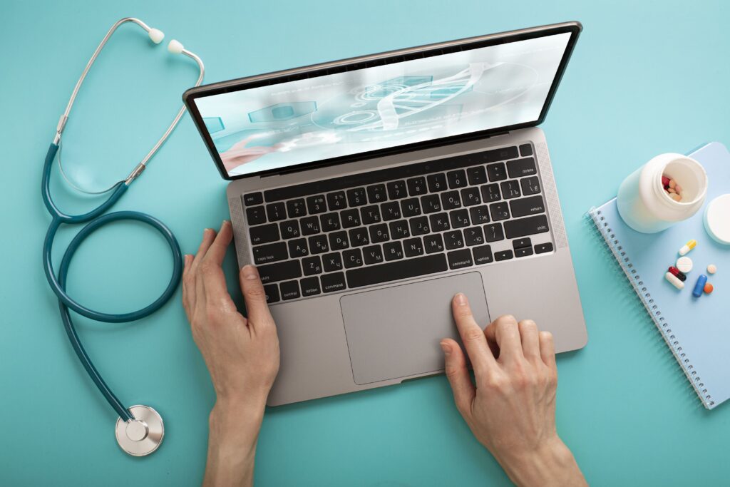 Manos trabajando sobre un portátil con interfaz médica, representando digitalización y gestión clínica avanzada