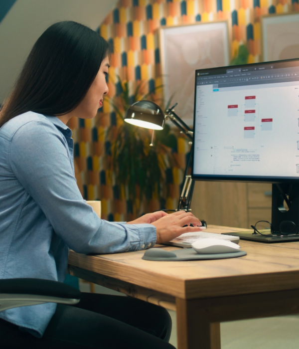 Mujer trabajando en su ordenador de escritorio desarrollando sitios web en un entorno productivo y organizado