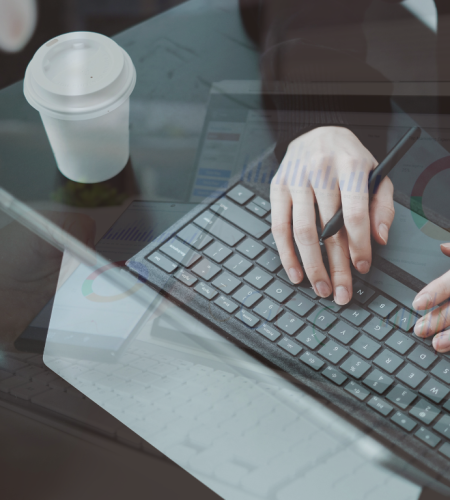Manos escribiendo en teclado con café y gafas sobre la mesa, reflejando una jornada laboral en diseño web y posicionamiento