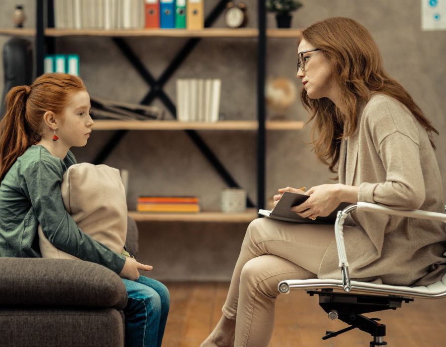 Alt: Psicóloga infantil en sesión terapéutica con niña pequeña.